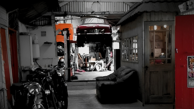 Clarke Bros garage with motorcycles, a couch, and classic cars