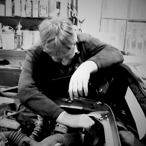 Person working on a vehicle engine in a workshop setting